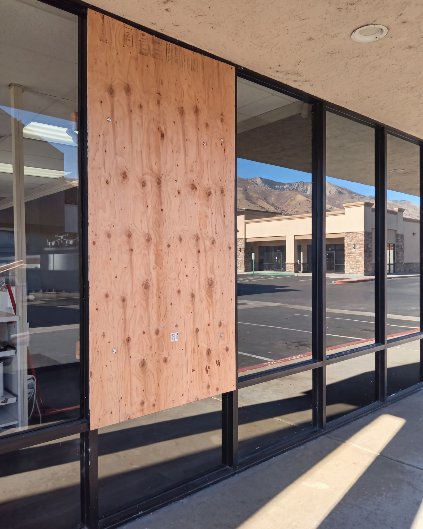 Sheet of plywood screwed over a broken storefront window, the opening secured and ready for new glass